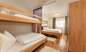 A cozy room with a bunk bed and a double bed.  
Large windows let in plenty of light and the wooden furniture creates a warm atmosphere.