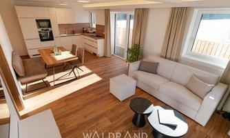 A modern apartment with an open living and dining area. Bright colors, wooden floors, and large windows create an inviting atmosphere.