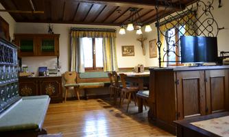 A cozy room with wooden furniture and a dining table. Large windows let in plenty of light.