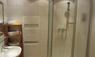 A modern bathroom with a shower, sink, and a towel warmer. The walls are brightly tiled, and there are clean towels on a shelf.