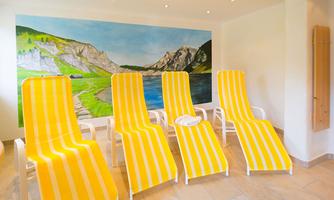 A bright room with yellow loungers. On the wall, there is a large landscape painting.