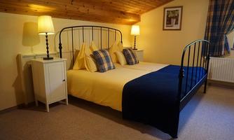 A cozy bedroom with a double bed and comfortable pillows. There are nightstands with lamps and inviting wooden decor.