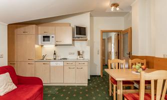 A bright kitchen with modern appliances and a cozy dining area. In the room, there is a red sofa and an inviting atmosphere.