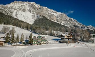 A picturesque alpine landscape with snow-covered mountains. In the foreground, cozy houses and snow-covered trees stand.