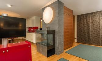 A modern living room with a television and an elegant fireplace. The room has wooden flooring and stylish rugs.