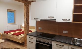 A cozy vacation apartment with a kitchenette and a sleeping area. The room is bright and cheerfully designed.