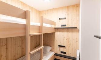 A simple room with wooden bunk beds. The walls are in a light wood tone.