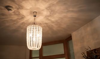 An elegant ceiling lamp with crystals that provides warm light. The shadow patterns on the wall create a cozy atmosphere.