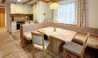 A cozy kitchen with a dining table and wooden details. Large windows provide plenty of natural light.