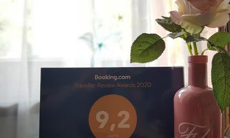 An award plaque from Booking.com with a rating of 9.2 for Hiasl Stubn. In the background, there is a vase with an artificial flower.