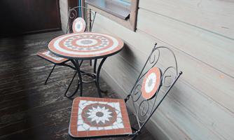A small bistro set with a round table and two chairs. The furniture features a decorative mosaic design on the surfaces.