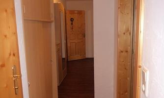 A bright hallway with wood paneling and a simple design. The walls are in neutral colors, and the lighting creates an inviting atmosphere.