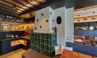 A modern restaurant interior with cozy seating. The walls are creatively designed, and there is a clock and an appealing lighting design.