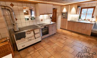 A modern kitchen with bright tiles and an elegant design. The equipment includes a stove, an oven, and a sink.