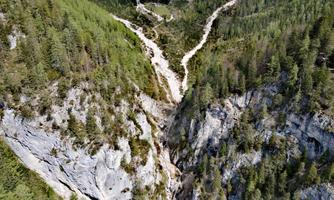 An impressive landscape with green forests and steep rocks. A clear river winds through the valleys.
