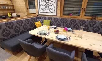 A cozy dining area with wooden decor and a large, bright table surface. The benches and chairs are modern and invitingly arranged.