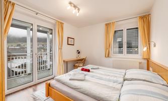A bright bedroom with a double bed and large windows. The decor is modern and cozy, perfect for a relaxing stay.