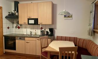A cozy kitchen with wooden cabinets and modern appliances. A table with chairs and a seating area invite you to linger.