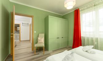 A modern room with green walls and a large wardrobe. The red curtains and the wooden floor create a cozy atmosphere.