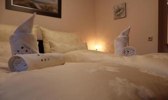 A cozy bedroom with a large bed and decorative towels. Soft light creates an inviting atmosphere.