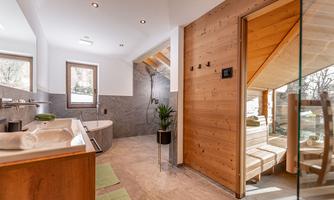 A modern bathroom with a freestanding bathtub and a wooden wall. Large windows provide plenty of daylight and a relaxing atmosphere.