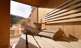 A cozy sauna room with wooden benches and a view of the mountains. A towel is ready to enjoy the relaxing atmosphere.