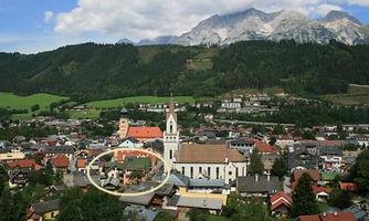 A picturesque town with a church and surrounding mountains. The colorful houses are idyllically situated under a clear blue sky.