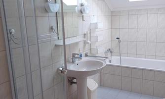 A bright bathroom with a skylight, a bathtub, and a shower. There is a sink and modern tiles.