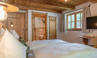 A cosy bedroom with two beds and wooden details. Large windows let in plenty of light and create an inviting atmosphere.
