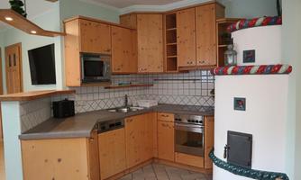 A modern kitchen with wooden cabinets and tiles. It contains appliances such as a stove, a refrigerator, and a sink.
