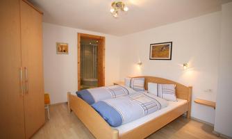 A cozy bedroom with a double bed and bright walls. A wardrobe and a bathroom are also visible.