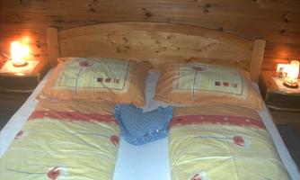 A cozy bedroom with a double bed and two pillows in soft colors. Soft lighting from two bedside lamps creates a warm atmosphere.