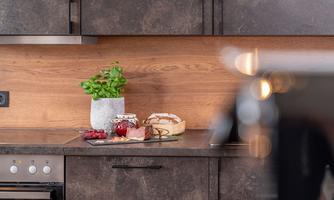 A modern kitchen with wood paneling and a gray countertop. Fresh herbs, baked goods, and fruit are on the countertop.