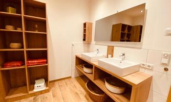 A modern bathroom with a double sink and a large mirror. Wooden storage and decorative baskets complement the appealing design.