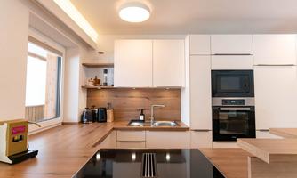 A modern kitchen with bright cabinets and wooden surfaces. The equipment includes a stove, an oven, and some kitchen appliances.