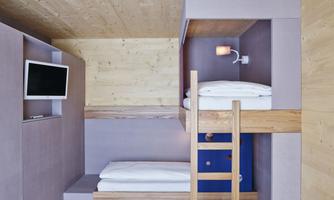 A modern room with a bunk bed and a television. The walls are painted in soft colors and there is a cozy atmosphere.