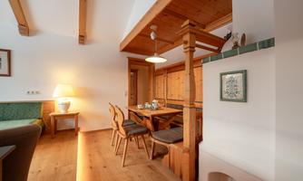 A cozy dining area with wooden paneling and elegant chairs. The room has large windows and a warm atmosphere, perfect for sociability.