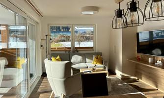 Bright living room with modern furniture and large windows. The room is furnished with a cozy sofa and stylish lamps.