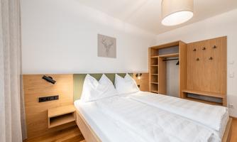 A modern bedroom with two beds and minimalist decoration. Bright colors and wooden details create a cozy atmosphere.