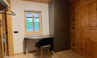 A cozy room with wood paneling and a desk. The window lets in plenty of natural light.
