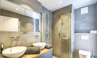 A modern bathroom with two sinks and a glass shower. The walls are in neutral tones, and there are elegant fittings.