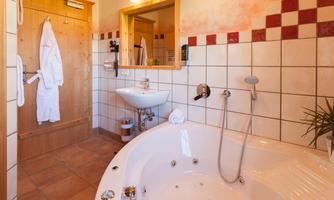 A cozy bathroom with a large whirlpool and modern sanitary facilities. The walls are brightly decorated and give an inviting impression.