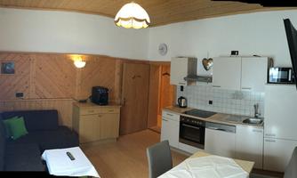 A cozy vacation apartment with a modern kitchen and an inviting living area. Wood paneling and bright furniture create a warm atmosphere.