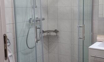 A modern bathroom with a glass shower stall and a white toilet. The floor is designed with gray pebbled stone.