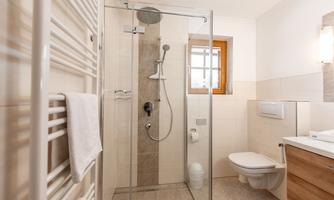 A modern bathroom with a glass shower cubicle and bright designs. It features a cozy atmosphere and practical furnishings.