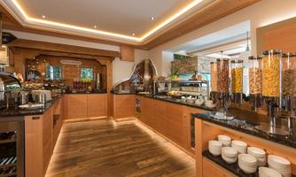 An inviting breakfast room with wooden paneling and bright lights. Various cereals and fresh dishes are ready on the counter.