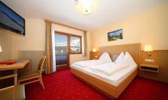 A cozy hotel room with two beds and a large window. The room is bright and modernly furnished.