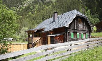 A charming wooden house with green shutters in a picturesque mountain landscape. Surrounded by trees and meadows, it offers an idyllic atmosphere.