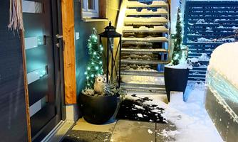 A cozy entrance area with a snowy ground. In the background, Christmas lights and a staircase can be seen.