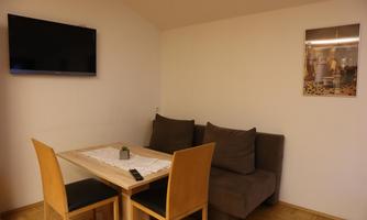 A cozy living area with a table and chairs. A television hangs on the wall, and a couch invites you to relax.